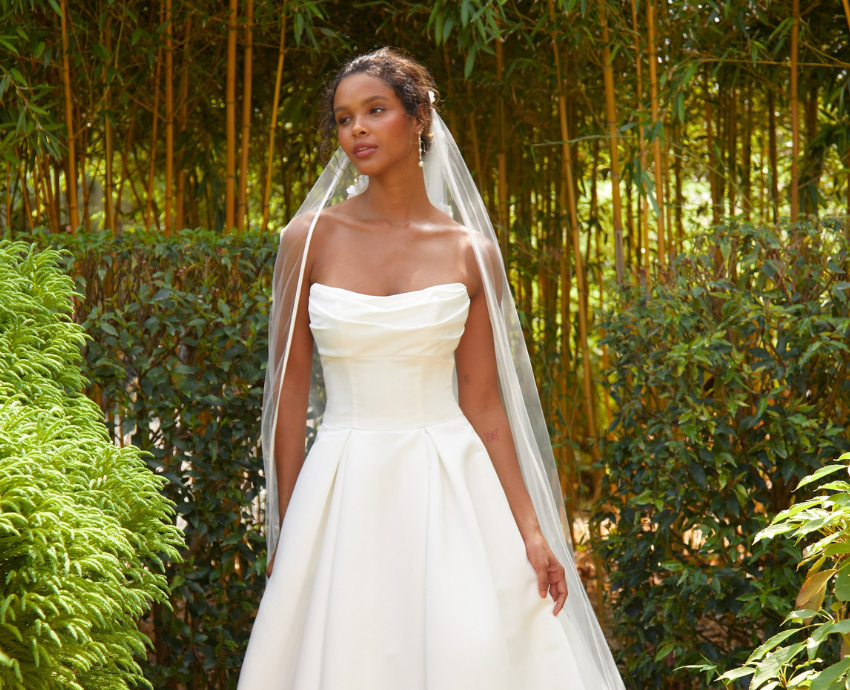 Michaela is a satin ballgown featuring a pleated skirt and lightly ruched bodice