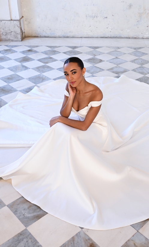 This gown has flattering off-the-shoulder sleeves and pleats across the body
